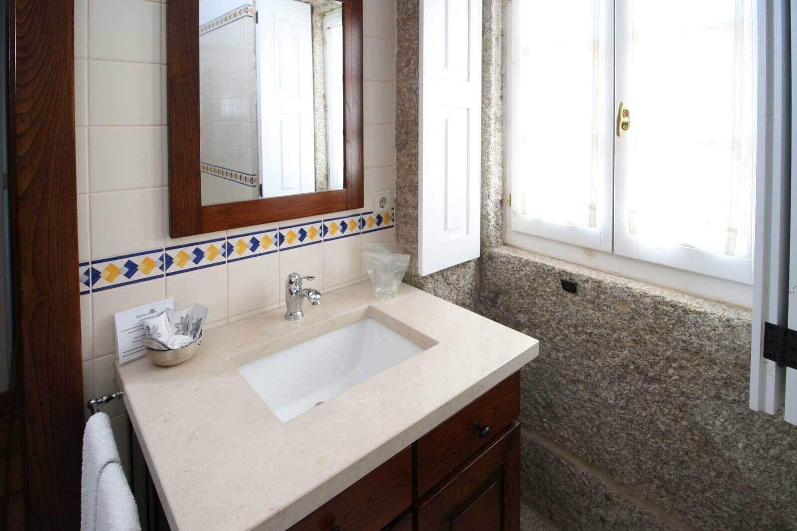 Une salle de bain avec un lavabo, un miroir et une fenêtre.