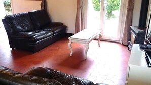 A living room with a black leather sofa, a white coffee table, and a fireplace. - Detached house in LE PARC DU MORVAN in Chalaux for 4 people. (Chalaux)