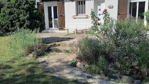 A house with a tiled roof, a front porch, and a garden with various plants and flowers. - Detached house in LE PARC DU MORVAN in Chalaux for 4 people. (Chalaux)