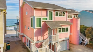 A two-story house with a garage, a small porch, and a staircase leading to the upper floor. - Ocean Dunes 1903 | Oceanfront, Spacious Layout, Views + Resort Amenities (Kure Beach)