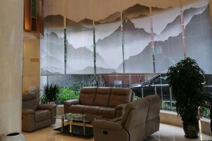 A lobby with a large window, a sofa, a coffee table, and a potted plant.
