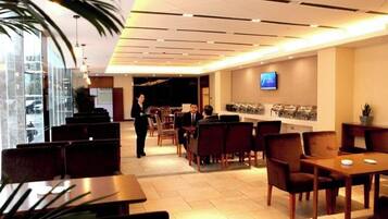 A hotel lobby with seating areas, a reception desk, and a television screen.