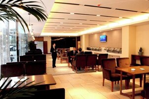 A hotel lobby with seating areas, a reception desk, and a television screen.