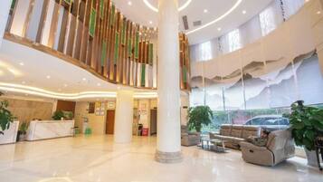 A spacious lobby with a central column, seating area, and a staircase.