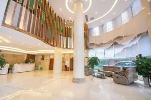 A spacious lobby with a central column, seating area, and a staircase.
