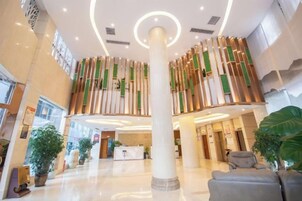 A spacious lobby with a central column, seating area, and reception desk.