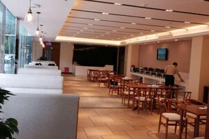 A modern restaurant with a bar area, seating arrangements, and a counter where a staff member is attending to customers.