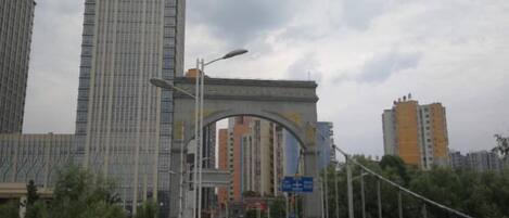 Una calle urbana con un gran arco, edificios altos y cielo despejado.