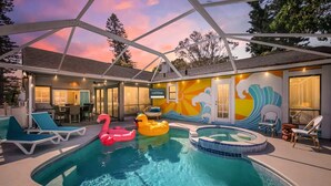 An indoor swimming pool with lounge chairs, inflatable toys, and a mural on the wall.