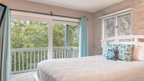 A bedroom with a large window, a balcony, and a bed with patterned pillows. - Relax & Enjoy Life! Updated Wild Dunes Condo (Isle of Palms)
