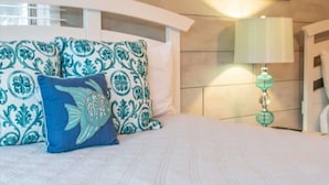 A bed with patterned pillows, a bedside lamp, and a white headboard. - Relax & Enjoy Life! Updated Wild Dunes Condo (Isle of Palms)