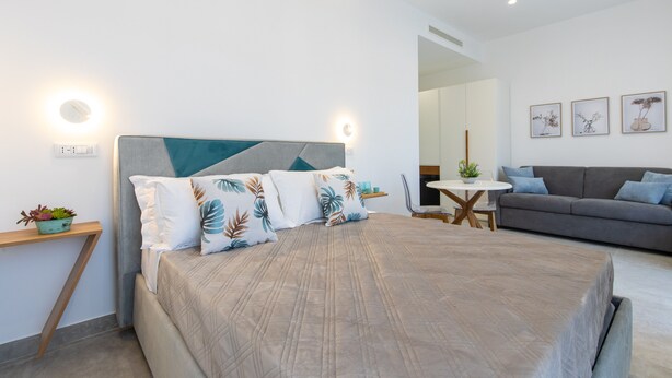 A modern bedroom with a bed, bedside table, and a grey sofa.