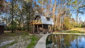 Un chalet rustique doté d’une terrasse en bois et situé devant un étang.