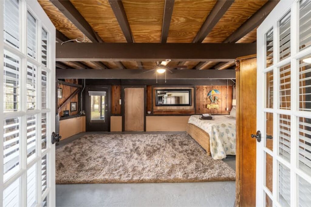 Une pièce spacieuse avec un plafond haut, des poutres apparentes, une grande fenêtre et un lit confortable.