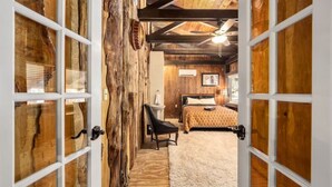 Une chambre à coucher rustique avec un mur en bois, un lit, une chaise et un ventilateur de plafond.
