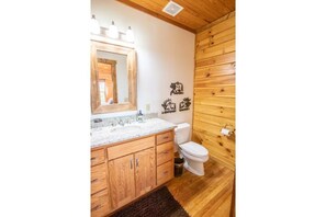 Een badkamer met houten wanden, een wastafel met spiegel en een toilet.