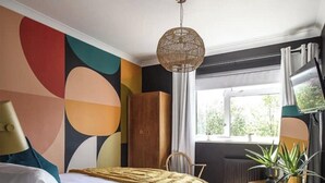 A bedroom with a bed, a dresser, a television, and a window with curtains. - 70s Inspired, 3-Bed Home in Rye with river views (Rye)