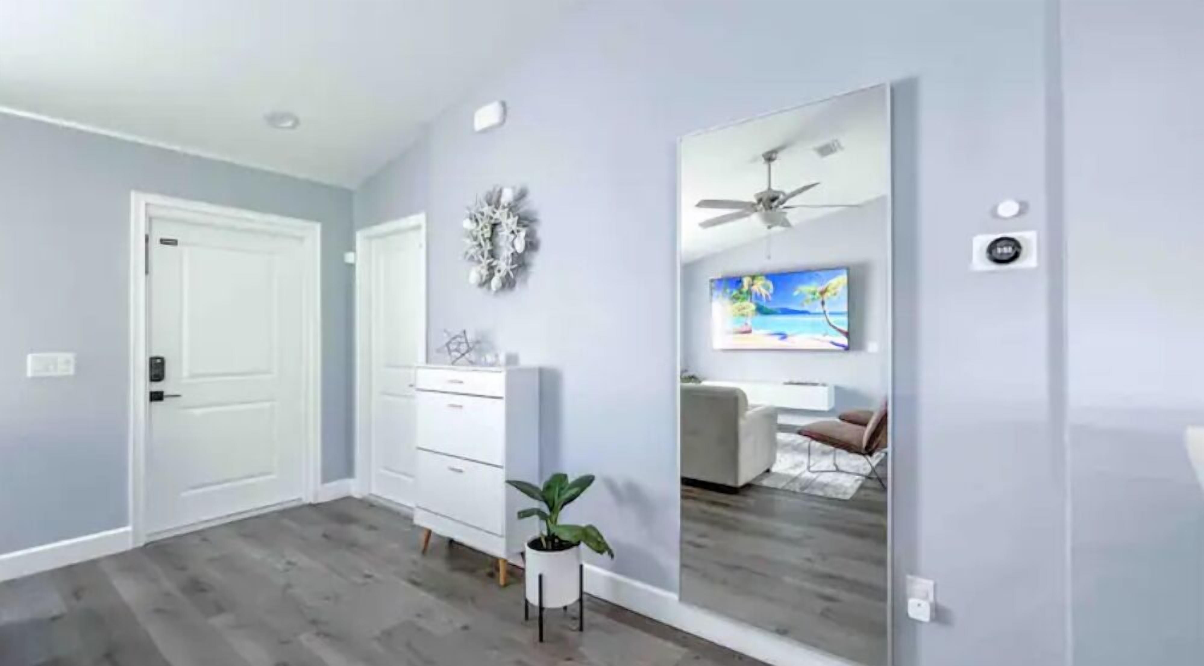 Une chambre moderne dotée d’un grand miroir, d’un ventilateur de plafond et d’un téléviseur.