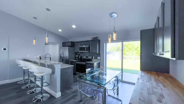 A modern kitchen with a glass island, bar stools, and a view of the outdoors.