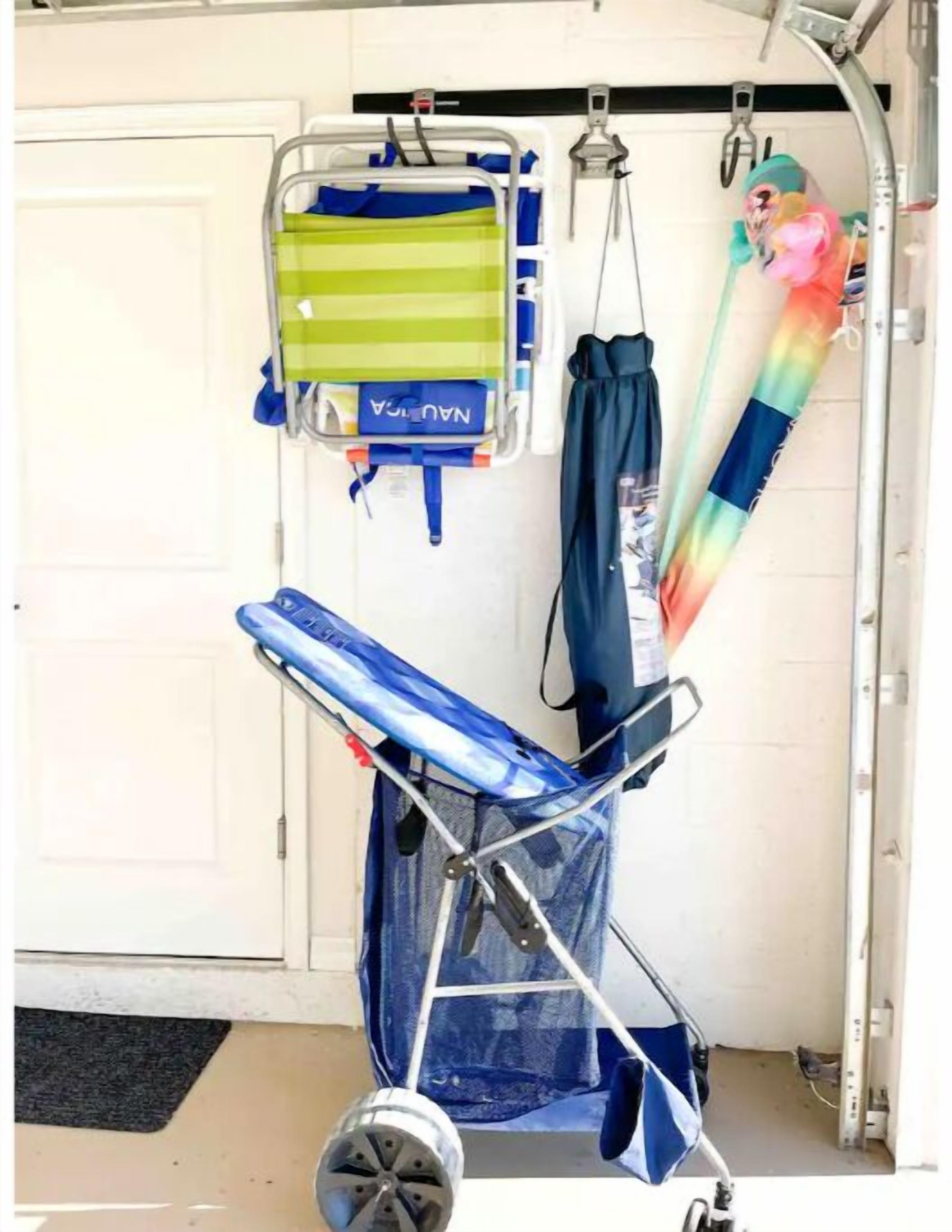 A medical stretcher with a blue cover, a green and blue striped bag labeled "NANULA," and a rainbow-colored umbrella hanging on a metal rack.
