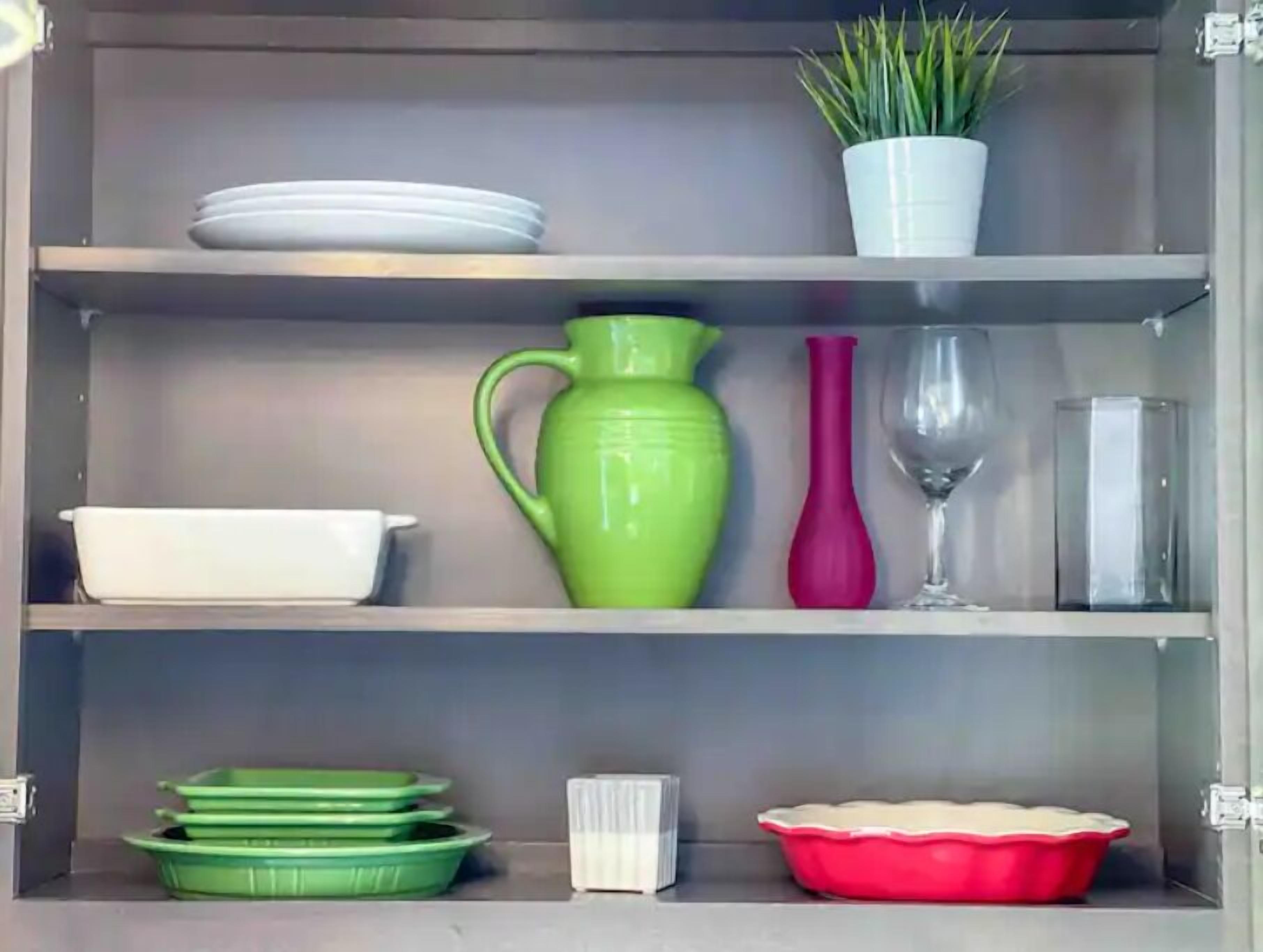 A kitchen cabinet with shelves containing various kitchenware items.