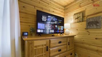 A wooden cabin interior with a flat-screen TV mounted on a wooden cabinet displaying various streaming services.