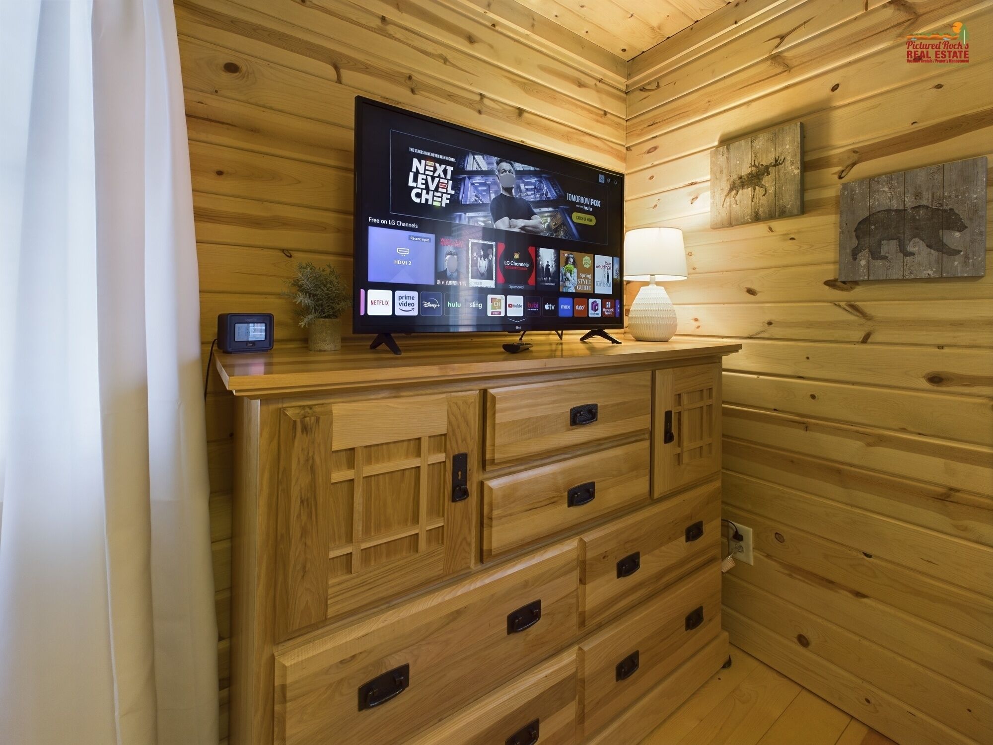 Interior de una cabaña de madera con un televisor de pantalla plana montado en un mueble de madera que muestra diferentes servicios de streaming.