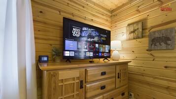 Interior de una cabaña de madera con un televisor de pantalla plana montado en un mueble de madera que muestra diferentes servicios de streaming.