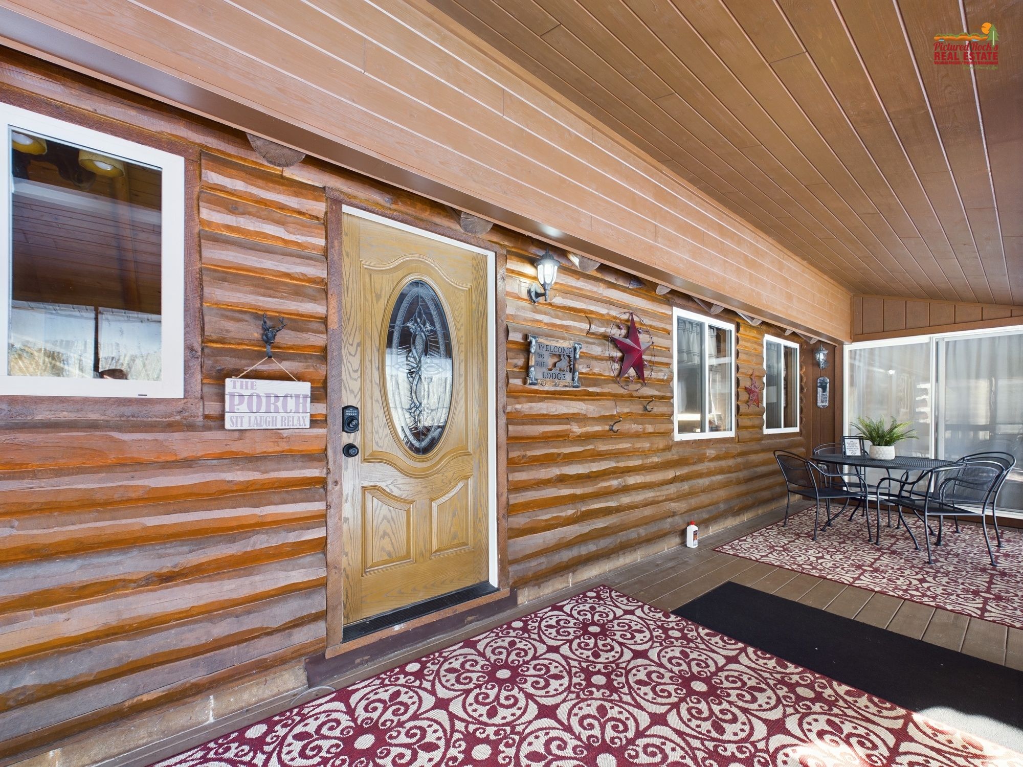 A log cabin-style building with a wooden exterior, a central door with a glass panel, and a seating area with a table and chairs.