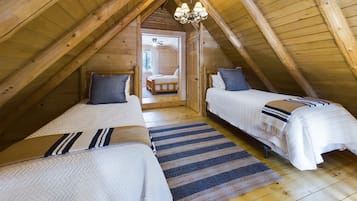 Un dormitorio acogedor en el ático con dos camas, vigas de madera, una araña y vistas al exterior.