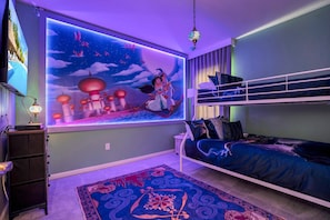 A bedroom with a bunk bed, a large wall mural, and a patterned rug.