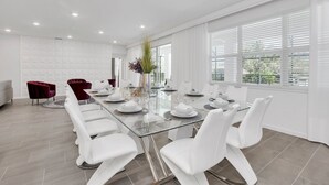 Une salle à manger moderne avec une table en verre, des chaises blanches et une chaise rouge.