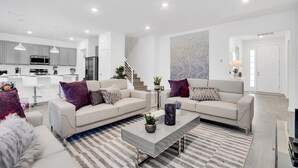 Un salon moderne avec un canapé, une table basse et un escalier menant à une salle à manger.