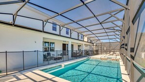 Une piscine intérieure dotée d’un toit en verre, entourée de chaises longues et bordée d’une allée couverte.