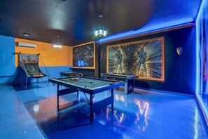 A pool table with a blue floor, a billiards rack, and a pool cue.