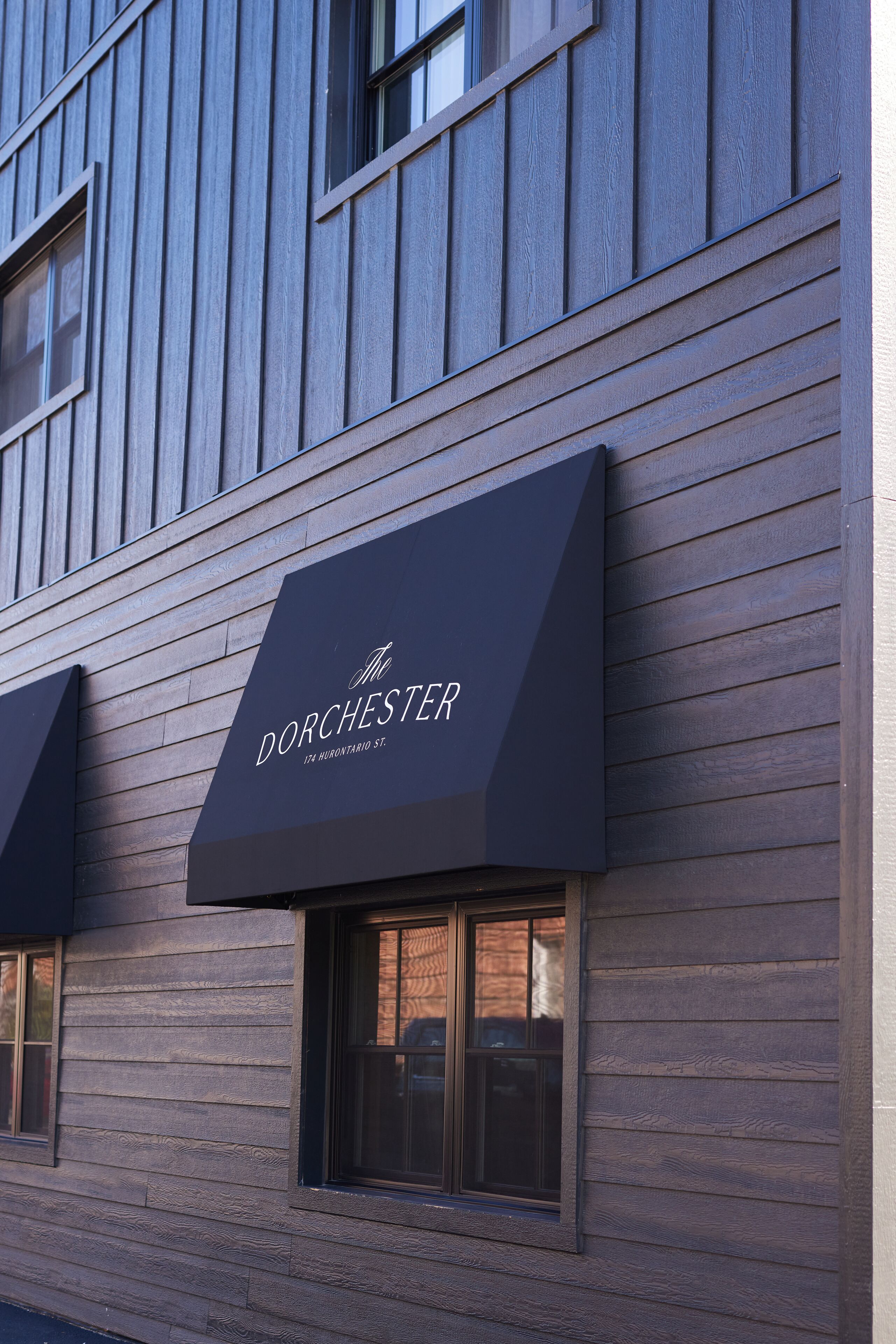 A building facade with a dark awning displaying the name "The Dorchester" and an address.