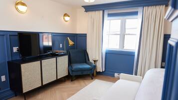 Una habitación de hotel con una cama, un escritorio con computadora, una silla, un televisor y una ventana con cortinas.