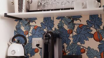 A kitchen counter with a coffee maker, kettle, and a framed picture above.