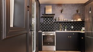 Una cocina moderna con armarios negros, horno de acero inoxidable y salpicadero de azulejos negros.