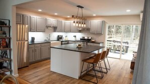 Une cuisine moderne dotée d’un grand îlot central, de planchers en bois et offrant une vue sur l’extérieur.