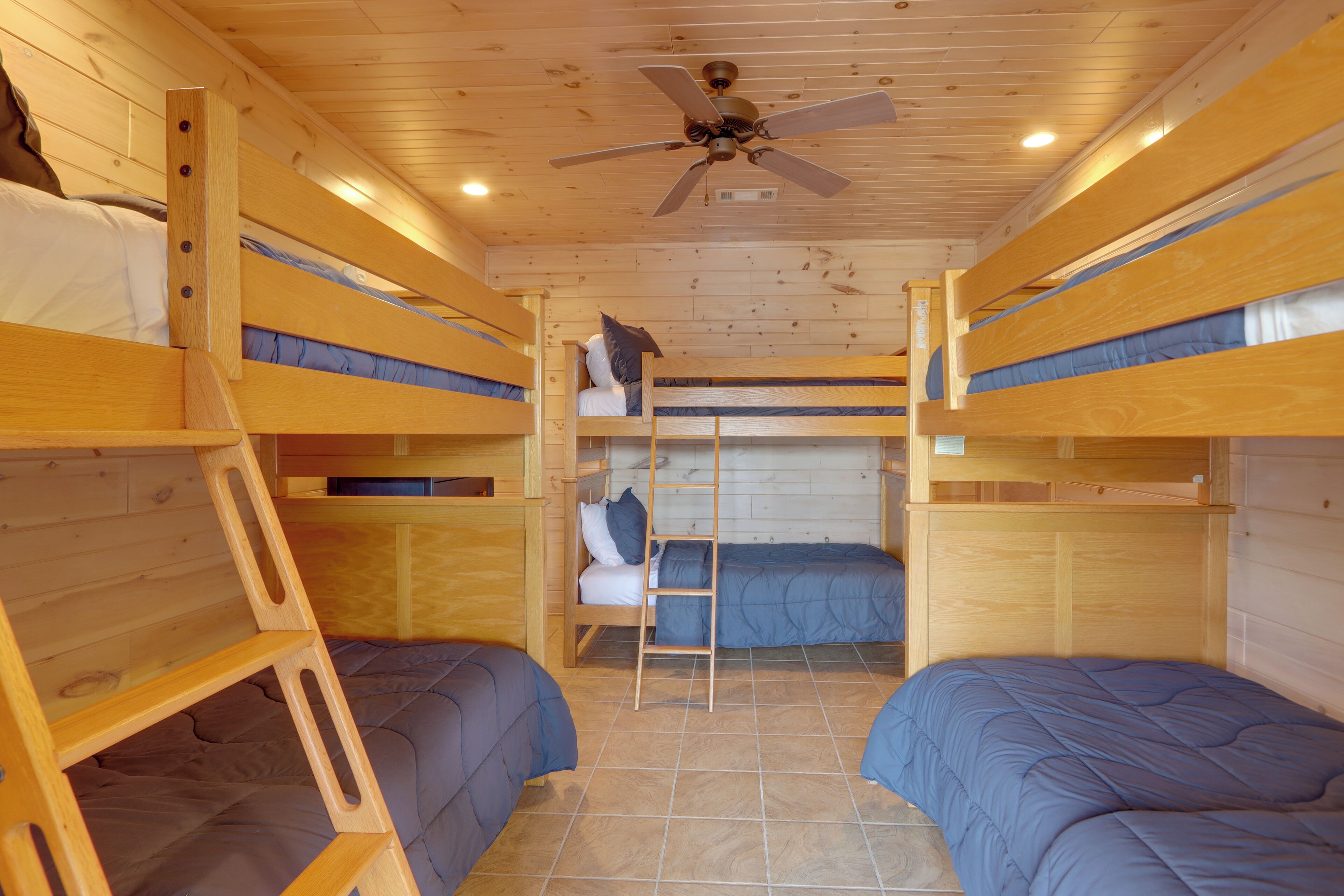 A cabin with bunk beds, a ladder, and a ceiling fan.