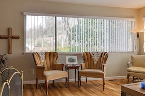 Relax in this inviting living room with a large window, two armchairs, and a small table.