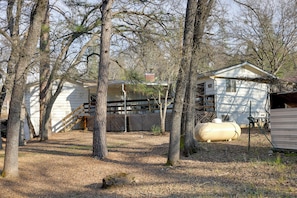 Surrounded by mature trees, this property features a main house with a covered porch and a large water tank.