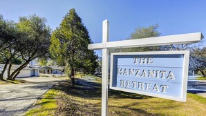 Placa de 'The Manzanita Retreat', com boa visibilidade da área ao redor, incluindo árvores e um edifício ao fundo.