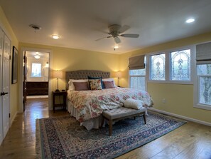 Una camera da letto con un letto grande, una ventola a soffitto e vista all'esterno da una finestra.