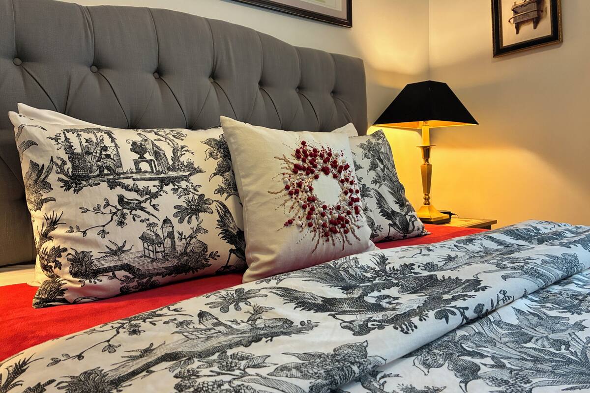 Un lit avec une literie à motifs, une tête de lit capitonnée et une lampe de chevet.