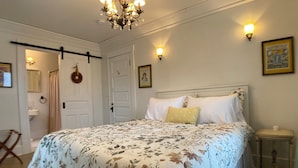 Une chambre à coucher avec un grand lit, un lustre, une porte et une table de chevet.