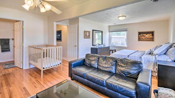 A spacious living room with hardwood flooring, a leather sofa, a glass coffee table, a ceiling fan, and a crib. - Spacious Chesapeake Home w/ Pool Table! (Chesapeake)