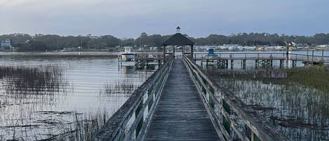 Un muelle de madera se adentra en aguas tranquilas, con un pabellón al final.