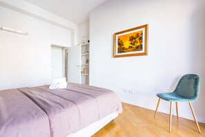 Una camera da letto con un letto, una sedia, un armadio e un quadro appeso al muro.